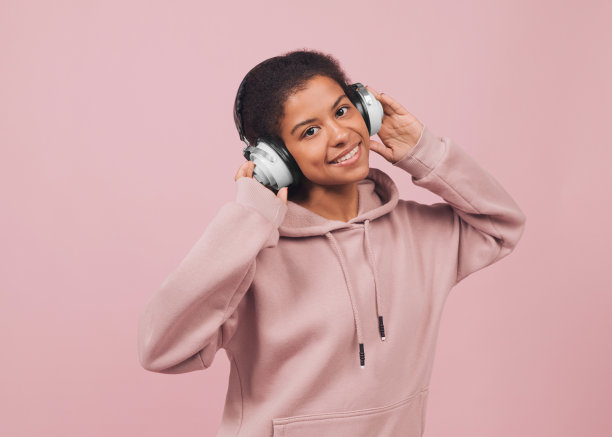 快乐的美丽年轻女子听音乐耳机。图片下载