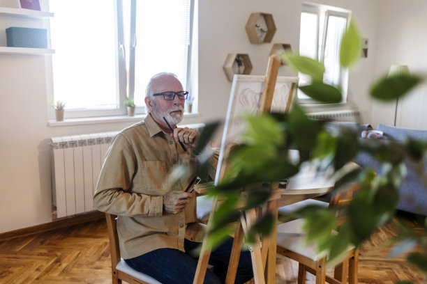 老人在画布上画画。图片下载