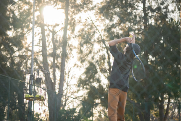 一个小男孩在网球训练中练习发球的完整镜头图片下载