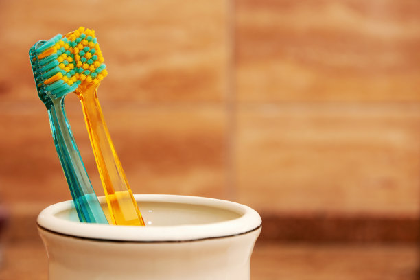 彩色牙刷在浴缸里的白色杯子里图片下载