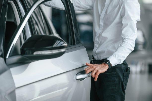 打开门。一个穿白衣服的年轻人在汽车经销店里图片下载