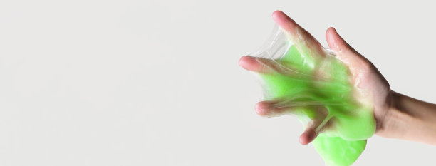 手玩纹理黏液在白色背景。十几岁的手拿着绿色闪亮的粘液与泡沫，伸展粘稠的物质。十几岁的女孩把黏糊糊的玩具挤到一边。液体的玩具。Handgum图片下载