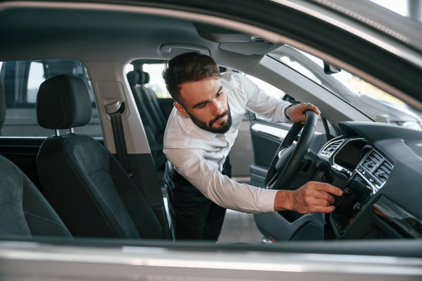 检查汽车沙龙。一个穿白衣服的年轻人在汽车经销店里图片下载