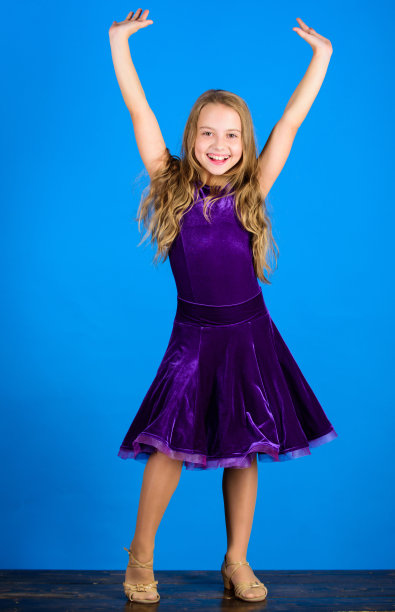 童装看起来很可爱。交际舞服装的时尚概念。对演唱会服装满意的童装舞者。交际舞的服装。舞厅时尚。女孩穿天鹅绒紫色连衣裙图片下载