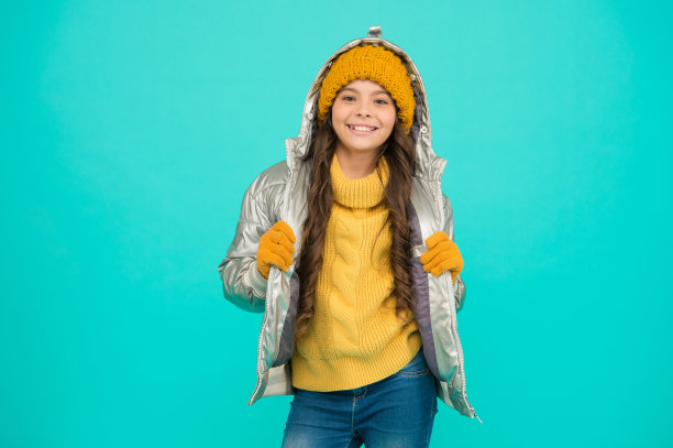 微笑的少女穿着棉袄或羽绒服，准备在舒适和温暖中度过寒假和童年的活动图片下载