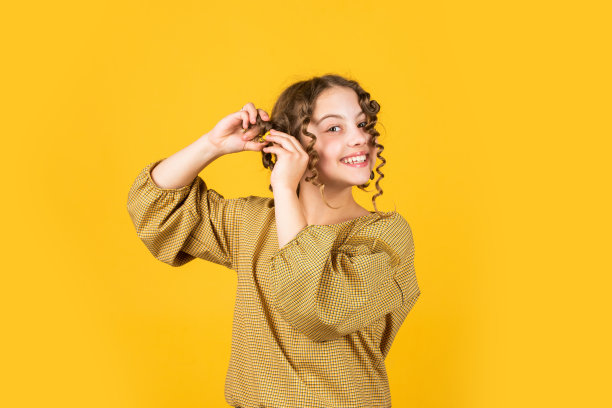 健康的长发。儿童头发护理。小女人用卷发器梳理头发。美丽与时尚。小女孩有卷发器乳头状突起。儿童美发店图片下载