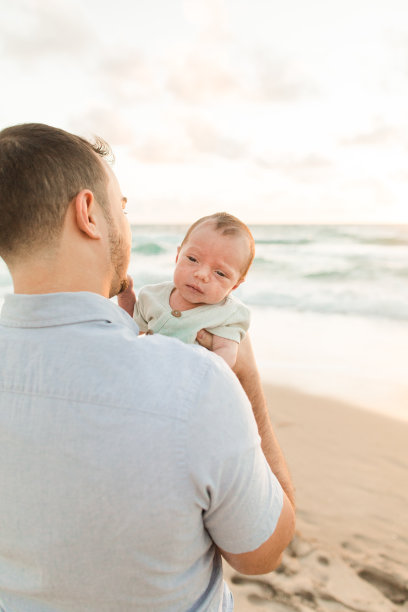 2022年11月，佛罗里达州棕榈滩海岸，一位年轻的父亲在金色日出时依偎着他刚出生的儿子图片下载