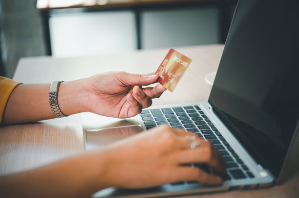 年轻女子持有信用卡和使用笔记本电脑。女商人在咖啡馆工作。网上购物，电子商务，网上银行，花钱图片下载