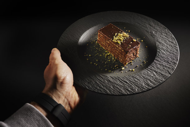 巧克力蛋糕，黑色背景上有核桃和开心果。自制糕点图片下载