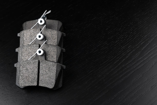 一套新的汽车零部件。新的刹车片在黑色木制背景上，复制空间。一组制动部件汽车商店或汽车服务的概念。图片下载