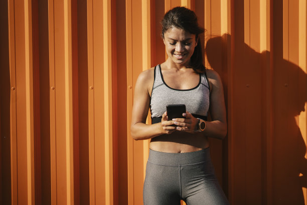 穿着运动服的漂亮女孩在打电话。图片下载