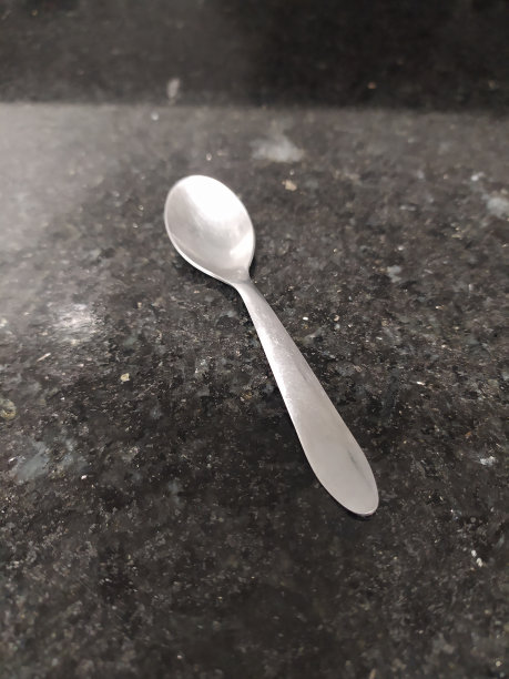 一把茶匙打在黑色大理石表面上图片下载