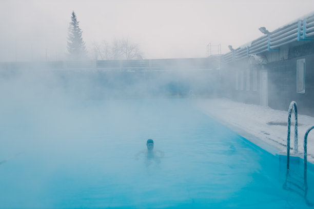 适合的游泳运动员训练游泳在开放的冬季游泳池有雾。地热户外水疗概念，图片下载
