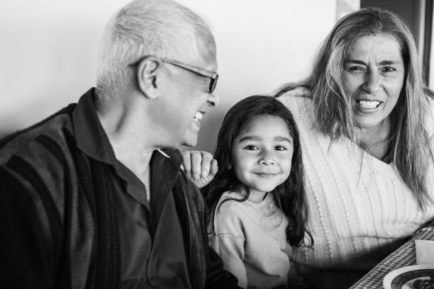 快乐的拉丁祖父母有乐趣与孙女在天井家吃饭-专注于女孩的脸-黑白编辑图片下载