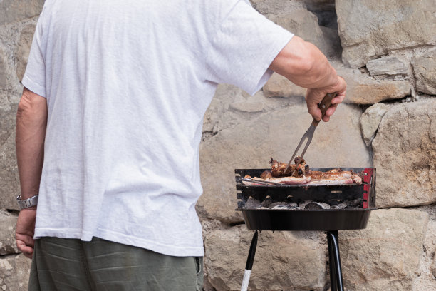 一名男子在烤肉架上烤肉图片下载