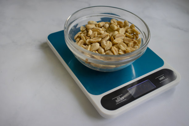 电子厨房秤，浅色背景上的花生图片下载