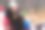 在冬天的森林里，漂亮的女人拿着智能手机和热咖啡坐在雪橇上图片下载