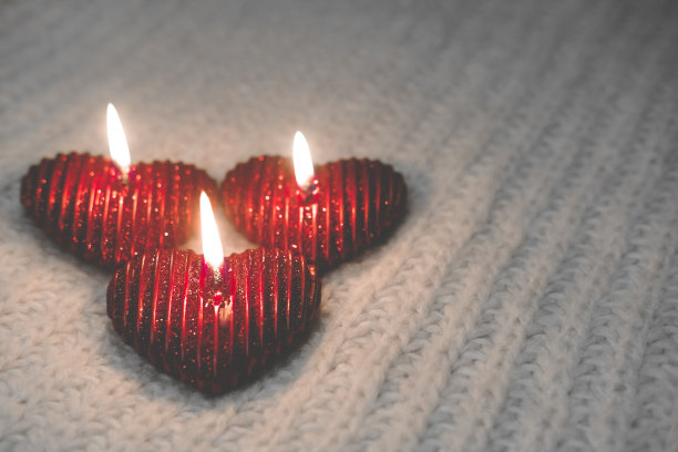 温馨温馨的情人节。三支红烛燃烧，爱情温暖。燃烧的蜡烛和针织元素组成。庆祝理念，浪漫之夜图片下载