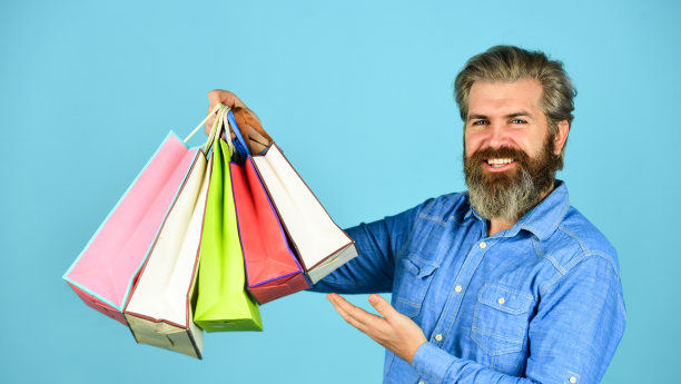 高兴的男人在网上购物。非常快乐的潮人在电子商店购物。积极的人喜欢购物。自己的生意。大胡子男人拿着纸袋。礼物图片下载