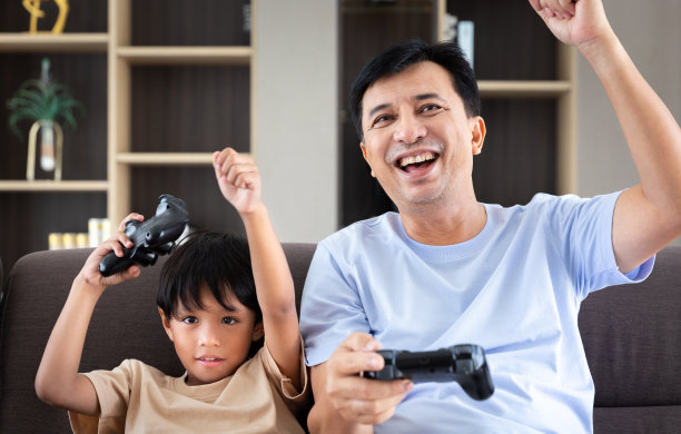 快乐的爸爸，爸爸和儿子在周末玩电子游戏站与控制游戏的远程操纵杆技术为家庭娱乐活动图片下载