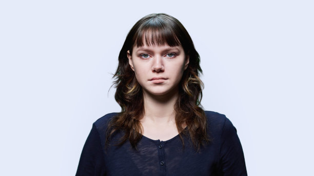 年轻女性在光背景上看着相机的头照肖像图片下载