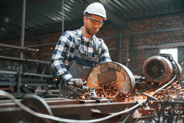 许多火花。切割金属。穿制服的工厂男工人在室内图片下载