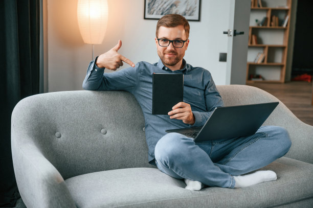 与图形平板。男性自由职业者在家里使用笔记本电脑。舒适的公寓图片下载