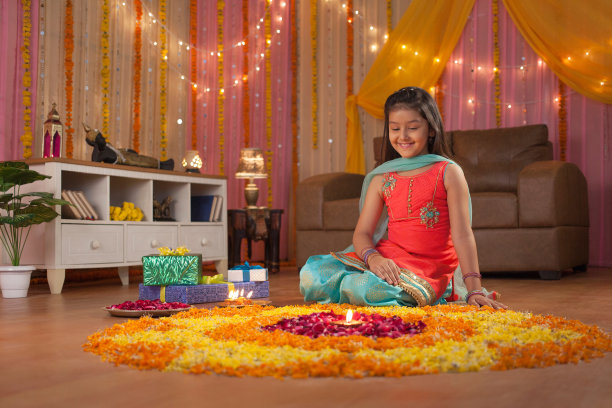 一个可爱和微笑的印度女孩坐在花rangoli附近的图片图片下载
