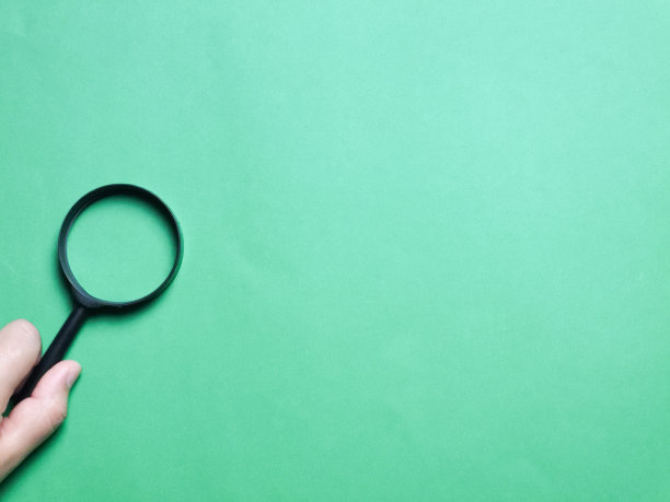 俯视图图像手持放大镜对绿色背景。图片下载