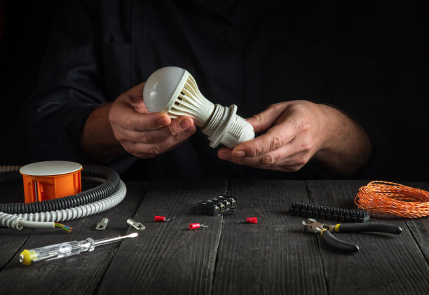 专业的电工师傅接灯泡。在车间工作时，工作人员在工作台上的特写图片下载