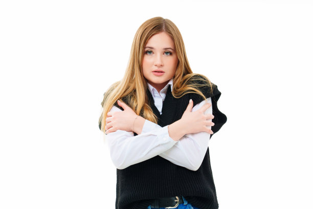 惊恐的金发女郎穿着一件黑色针织背心，手臂交叉在白色。图片下载