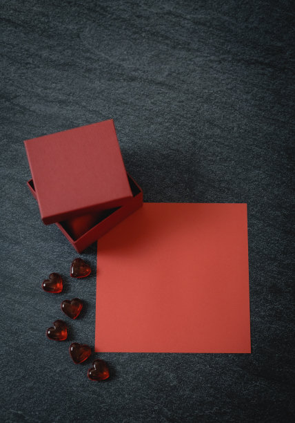 一个红盒子，一个玻璃心，一张白纸，背景是黑色的石头。图片下载