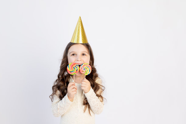 白色背景的帽子上戴着大棒棒糖的女孩，文字的空间，节日的概念图片下载