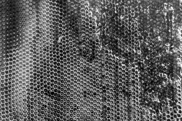 一滴蜜蜂蜜从充满花蜜的六角形蜂巢中滴下图片下载