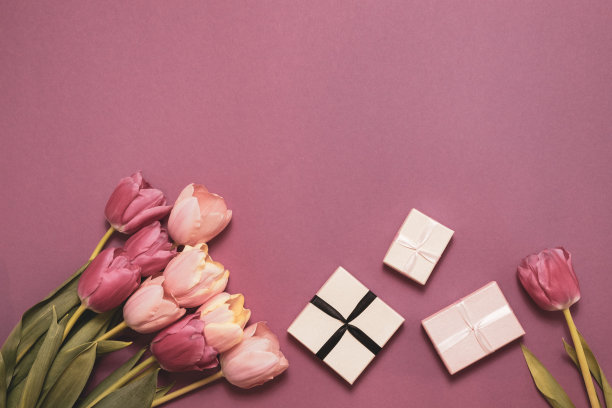 一束郁金香和一条项链作为节日礼物。粉红色背景上有美丽的花朵。节日概念-母亲节，情人节，复活节图片下载