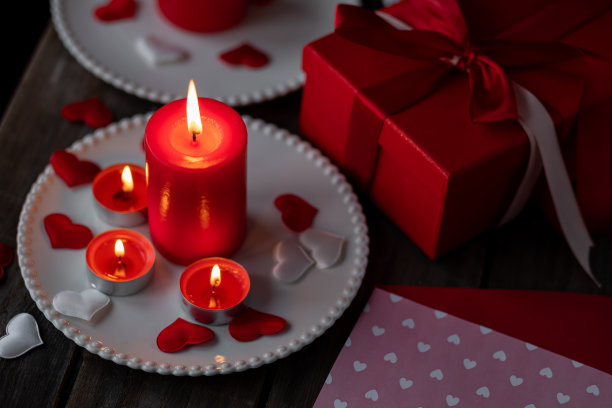 情人节庆祝活动。红色燃烧的蜡烛，爱心，礼品盒，明信片在黑暗的木制背景。节日快乐。餐桌装饰喜庆，气氛浪漫图片下载