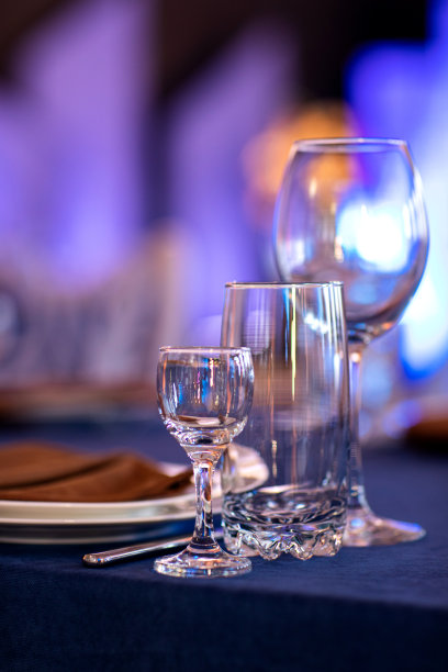 喜庆的圣诞节、婚礼、生日餐桌布置有蓝色桌布、橙色餐巾纸餐具、白色盘子、盛酒、水和烈性酒精饮料的玻璃杯。图片下载