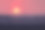 红艳艳的大太阳照在城市建筑的屋顶上，傍晚的夕阳。多云的天空，太阳落在房子后面图片下载