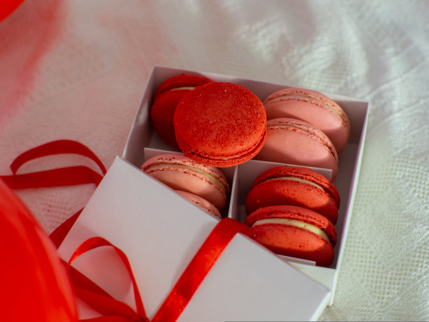 床上有一个盒子，里面有马卡龙饼干和红色气球图片下载