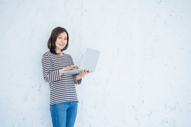 一个面带微笑的30岁女人在明亮的客厅里用笔记本电脑工作。图片下载