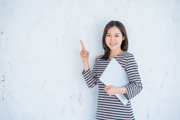 一个面带微笑的30岁女人在明亮的客厅里用笔记本电脑工作。图片下载