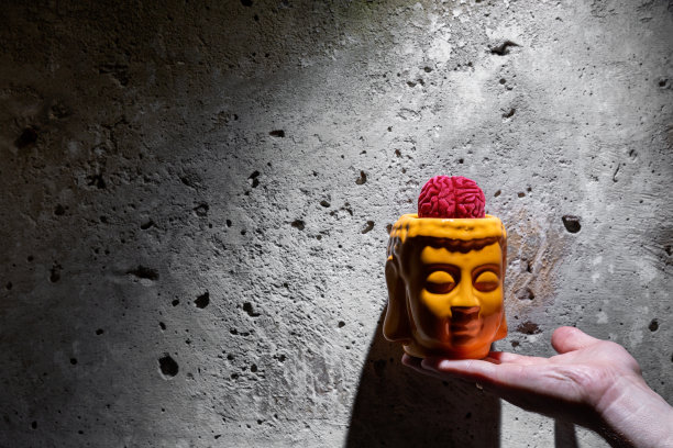 鸡尾酒里有一只手拿着一个玻璃杯，杯子里装着果酱脑，背景是一堵石墙图片下载