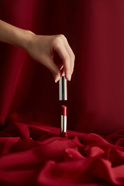 女性手在天鹅绒背景上打开红色唇膏图片下载