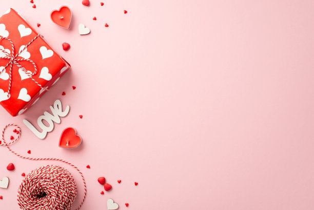 情人节的概念。顶部视图照片的礼盒心形蜡烛缠绕铭文爱和洒在孤立的粉彩粉红色背景与复制空间图片下载