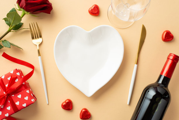 情人节的概念。顶部视图照片心形碟刀叉酒瓶酒杯巧克力糖果玫瑰和礼品盒在孤立的粉彩米色背景与复制空间图片下载