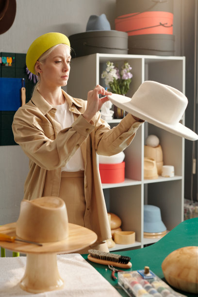 年轻的女工匠在聪明的休闲服装创造新的毡帽图片下载