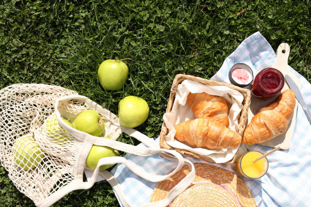 有果汁、果酱和羊角包的毯子，适合在绿草地上野餐图片下载
