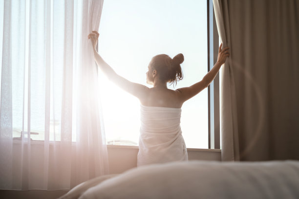 早晨女人裹着白毛巾望着窗外的后景照片。图片下载
