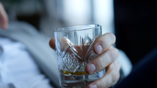 男子双手享受干邑饮料特写。投资领袖在酒店房间休息图片下载
