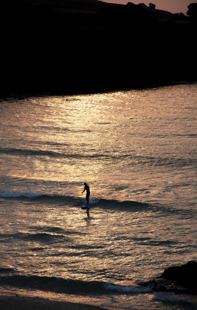 夕阳西下，冲浪者乘风破浪进入圣艾夫斯海滩图片下载